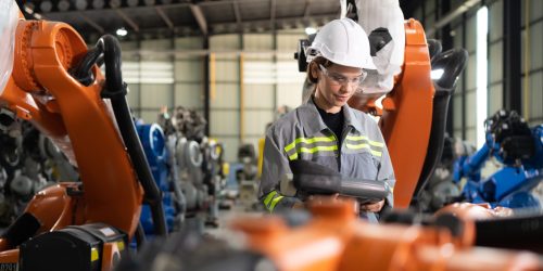 After installing a program on the robotic arm, a female engineer with a robotic arm controller performs a test run.